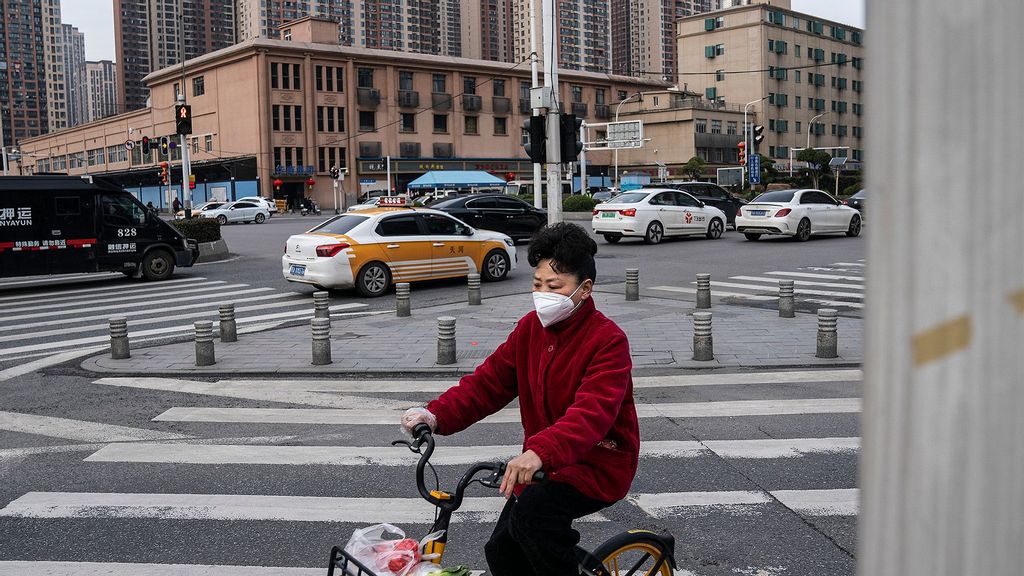 Resident wear a mask while ride through in front of a closed of Huanan seafood market on February 9, 2021 in Wuhan, Hubei Province, China. (Getty Images)