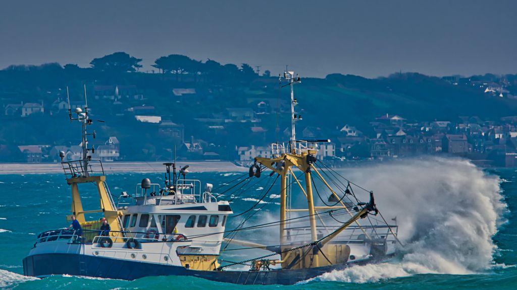 A fishing trawler navigates rough seas; some such vessels use massive nets to make illegal catches that economically harm Tonga and other Pacific island nations. (Larry Hookham/Unsplash)