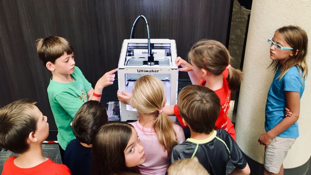 Children gather around a 3D printer. (Adam Winger/Unsplash)