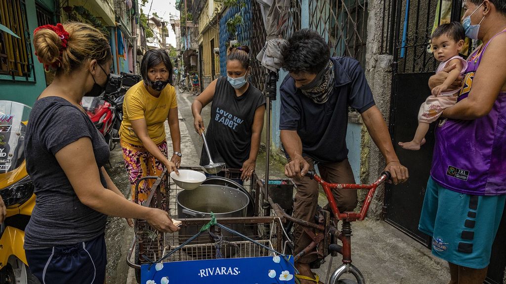 Volunteers use a pedicab to go door-to-door to give residents free chicken soup prepared in a community kitchen, at a slum area on August 12, 2021 in Marikina, Metro Manila, Philippines. (Ezra Acayan/Getty Images)