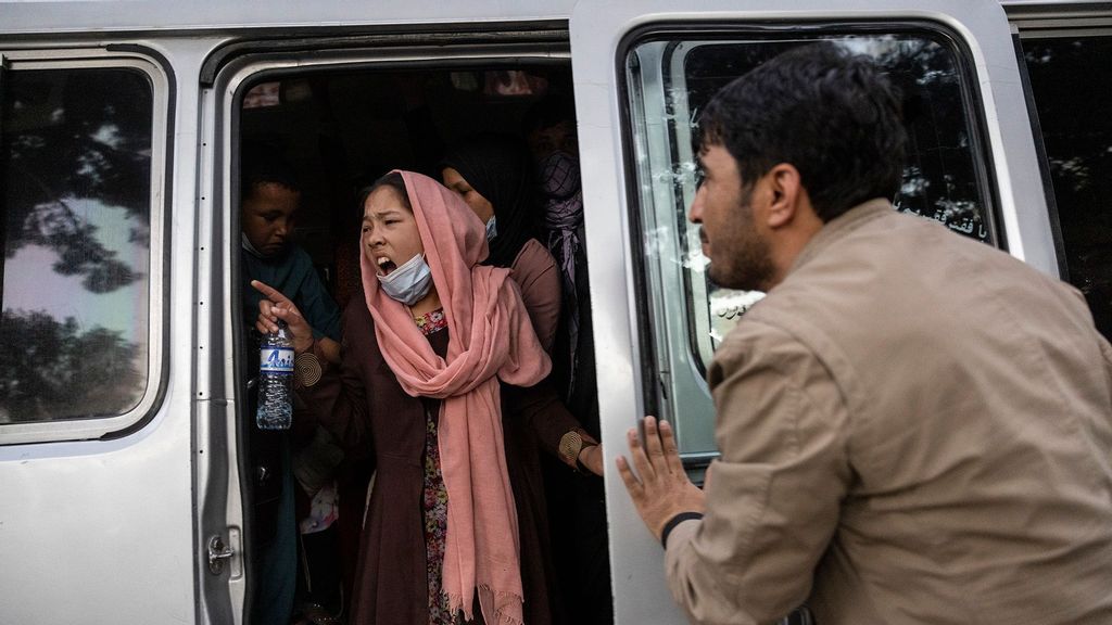 A woman yells for her family to hurry up as displaced Afghans from the northern provinces are evacuated from a makeshift IDP camp in Share-e-Naw park to various mosques and schools on August 12, 2021 in Kabul, Afghanistan. (Paula Bronstein/Getty Images)