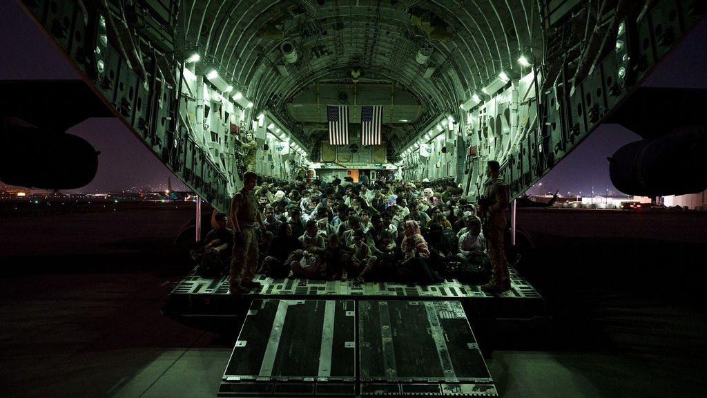 An air crew assigned to the 816th Expeditionary Airlift Squadron assists evacuees aboard a C-17 Globemaster III aircraft in support of the Afghanistan evacuation at Hamid Karzai International Airport on August 21, 2021 in Kabul, Afghanistan. (Taylor Crul/U.S. Air Force/Getty Images)