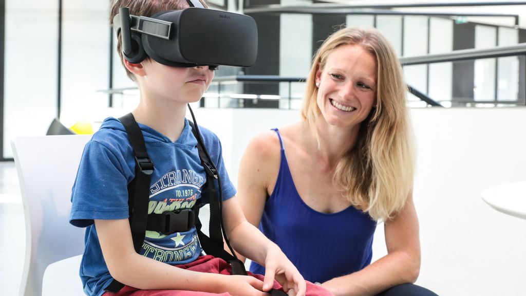 Jenifer Miehlbradt helps a 6-year-old child try virtual-reality games for the study, which found that head-torso coordination develops more slowly than previously thought. (EPFL/Alain Herzog)