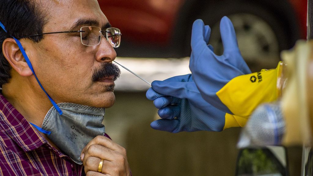 An Indian health official inside a COVID-19 mobile testing van uses a nasal swab to collect a sample from a man. (Yawar Nazir/Getty Images)